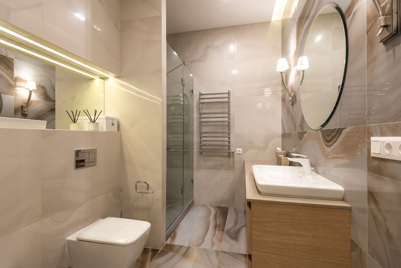 Elegant bathroom with marble tiles, large mirror, and modern fixtures.
