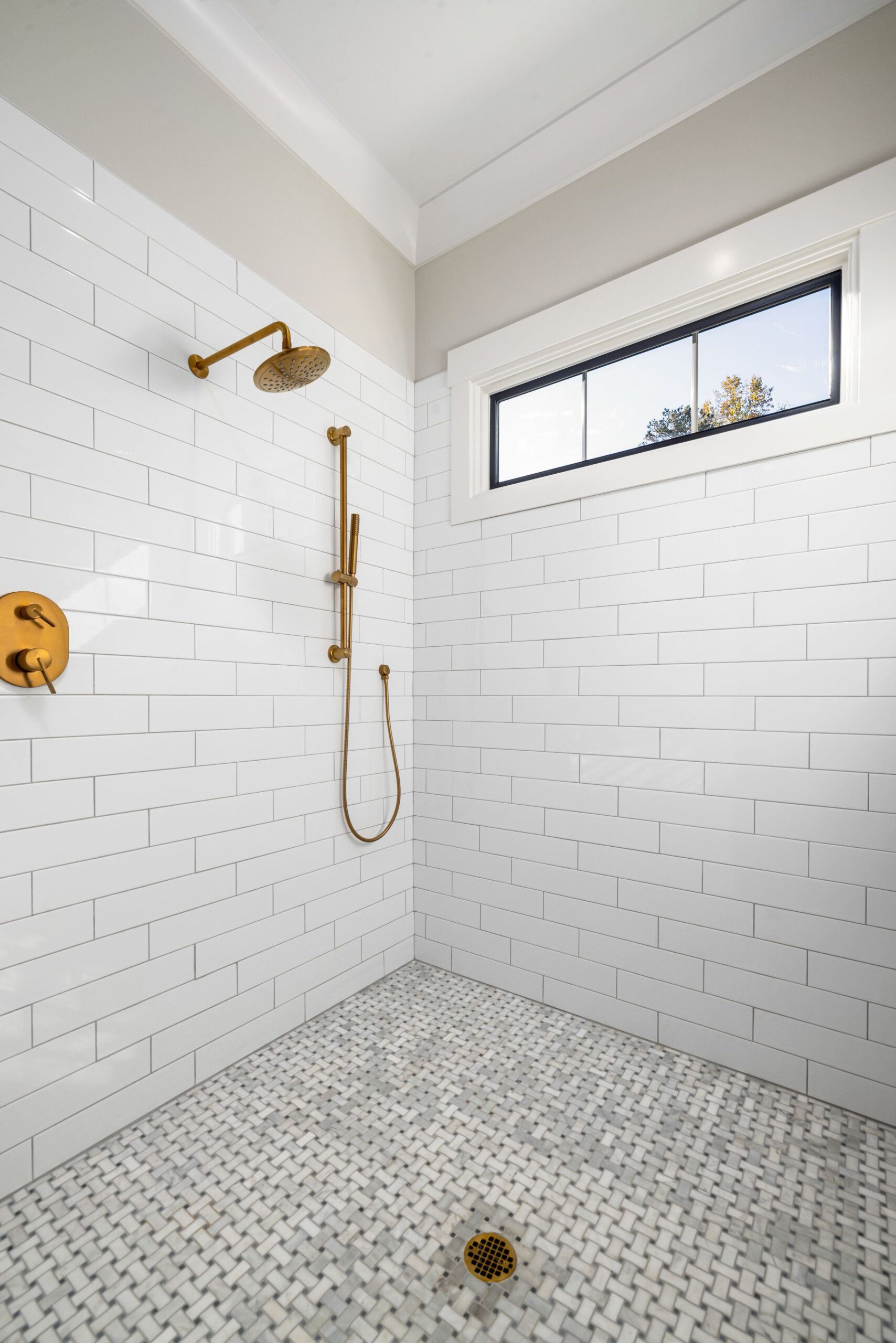 A sleek, contemporary bathroom with gold fixtures and white tiles.